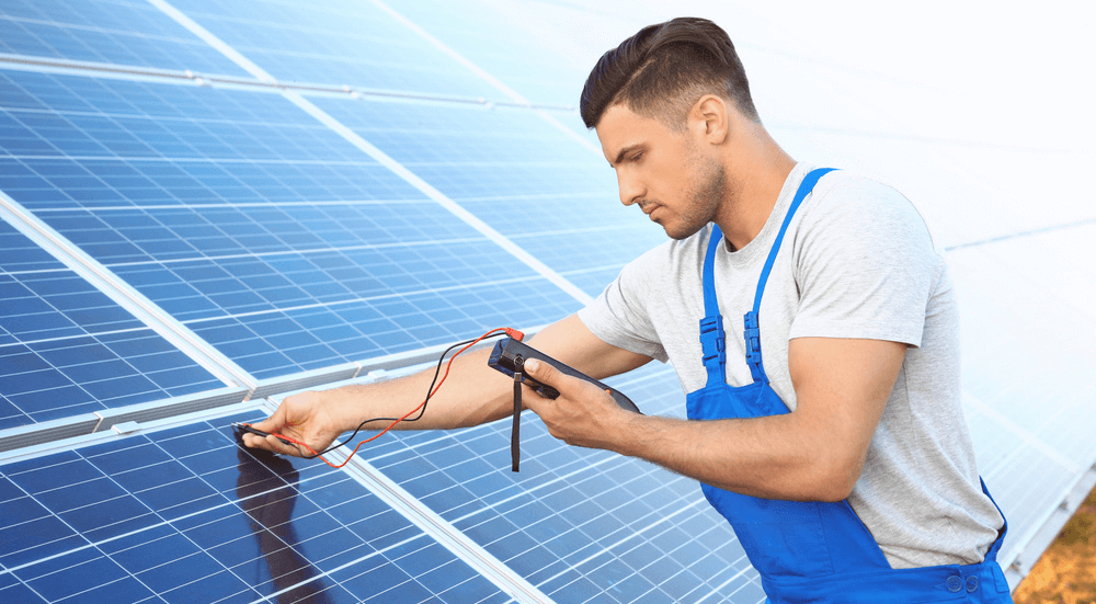 Technicien vérifiant un panneau solaire avec un multimètre en Tunisie